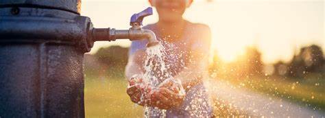 Boy washing hands in outdoor faucet